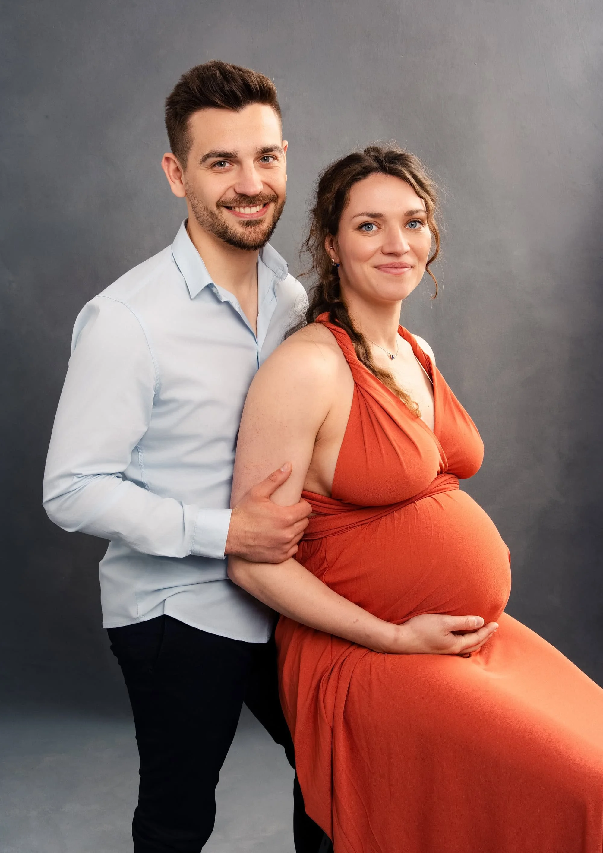 Couple de futurs parents photographié avec une robe orange au studio à Strasbourg