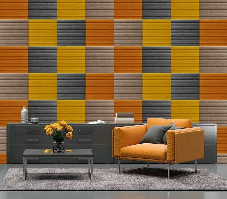 Moderan dnevni boravak sa šarenim, teksturisanim zidom od akustičnih filc panela, sivom komodom, narandžastom foteljom, sivim tepihom i crnim klub-stolom sa vazom žutog cveća. Funkcionalan i estetski snažan enterijer.