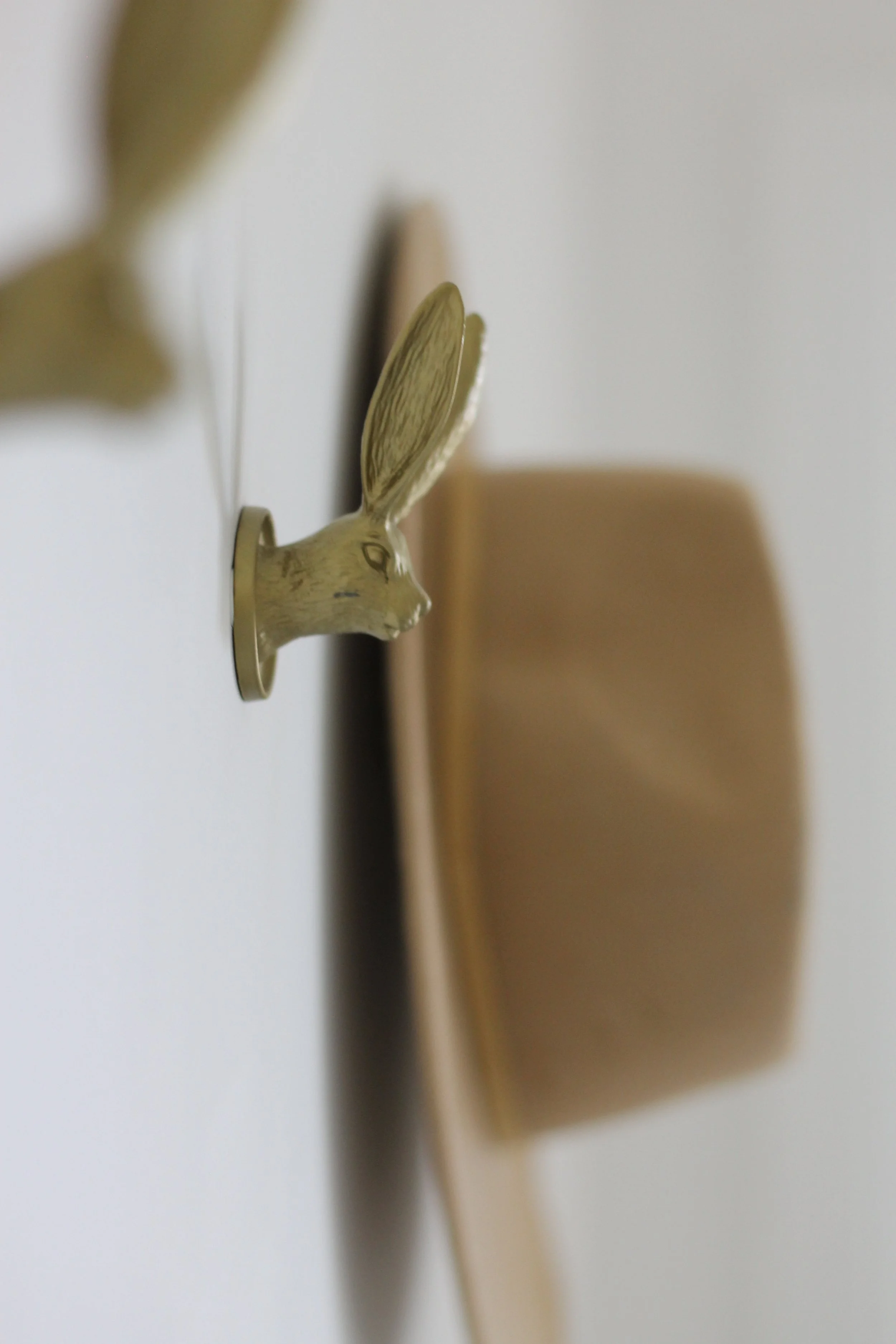 Close-up of a metallic rabbit-shaped door handle mounted on a wooden door, with a blurred background.