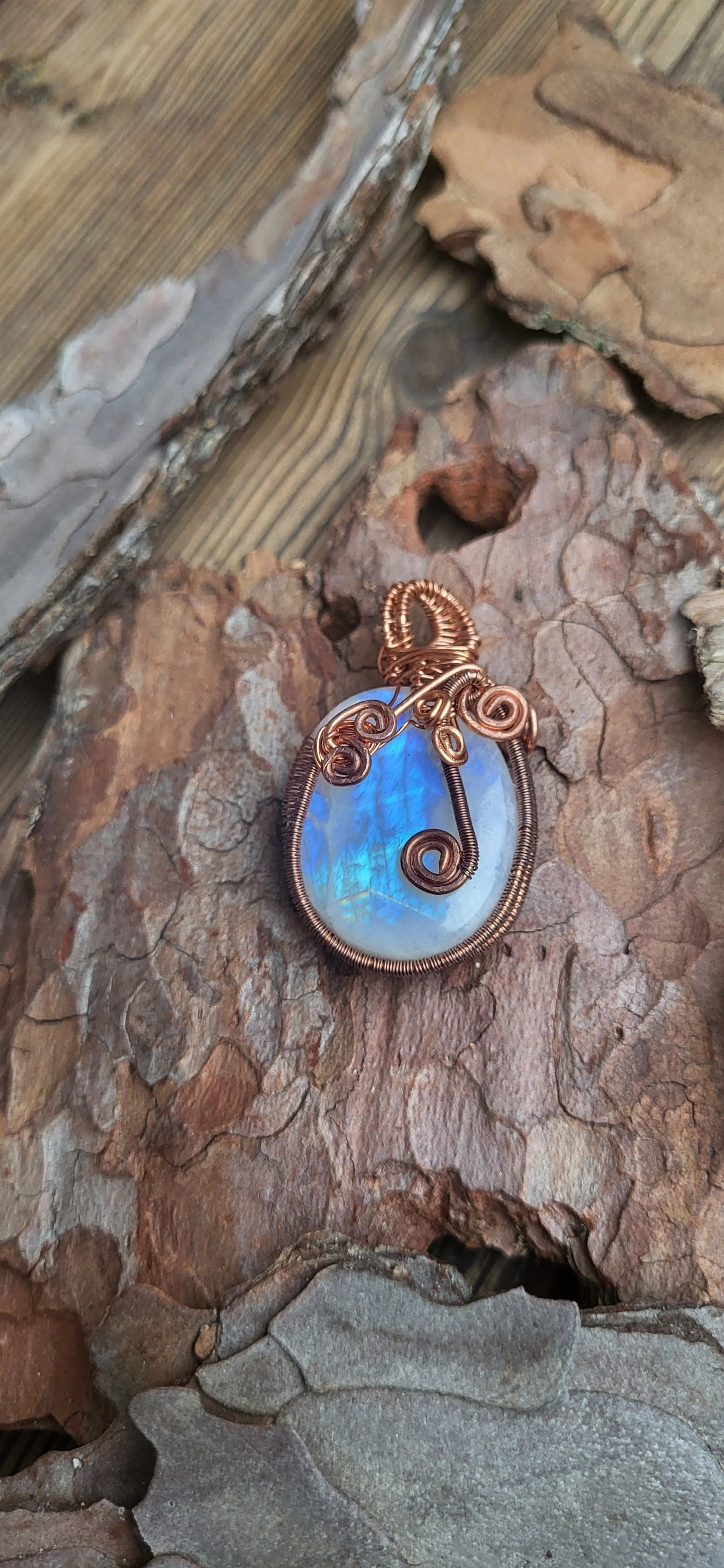 A pendant made of a moon stone cabochon wrapped in copper wire
