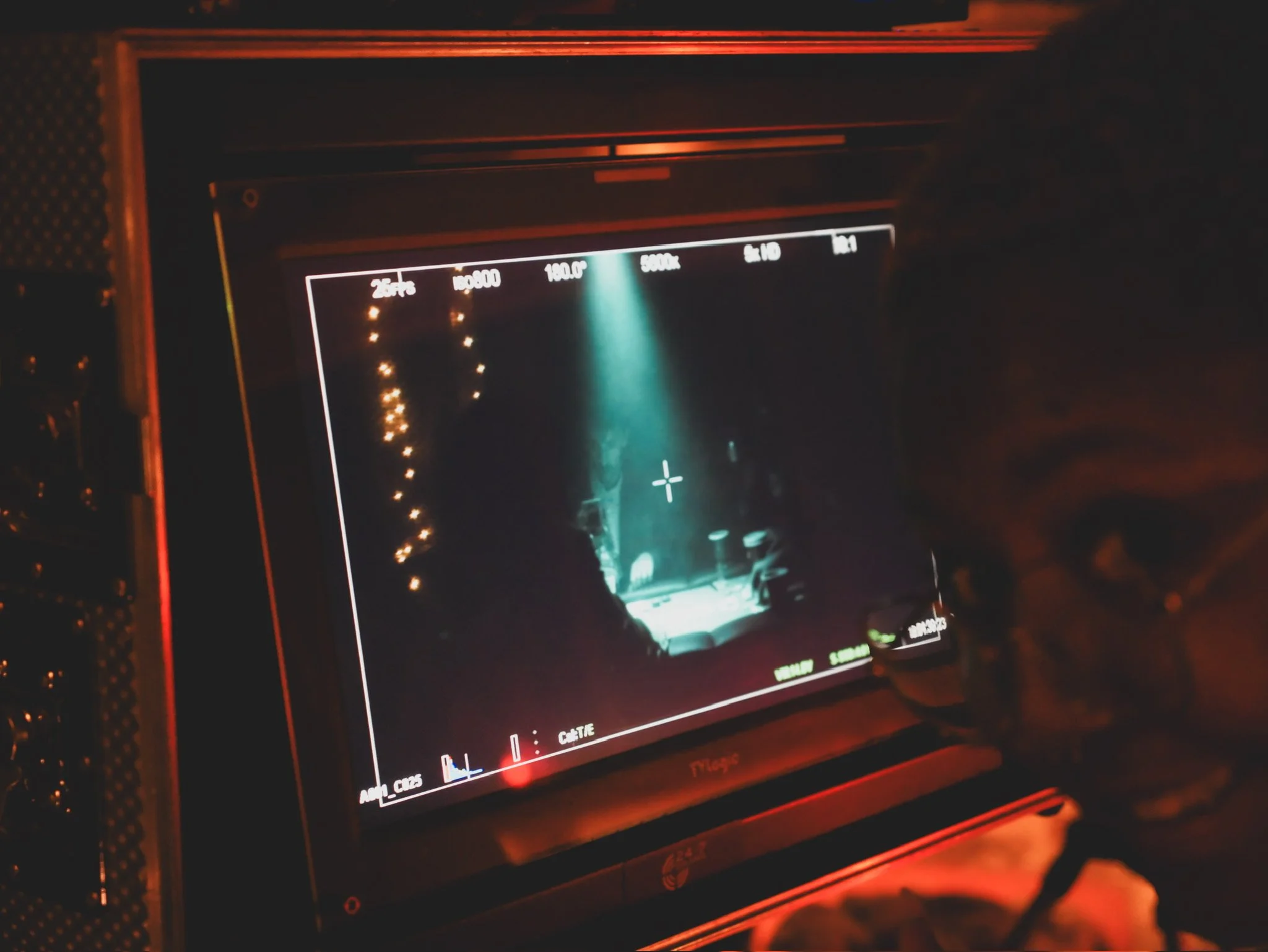 A camera's viewfinder display showing a nighttime street scene with a light beam illuminating the road, and a blurred vehicle passing by.