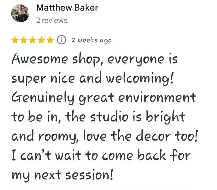 A five star Google review reading "Awesome shop, everyone is super nice and welcoming! Genuinely great environment to be in, the studio is bright and roomy, love the decor too! I can’t wait to come back for my next session!  - Matthew Baker"