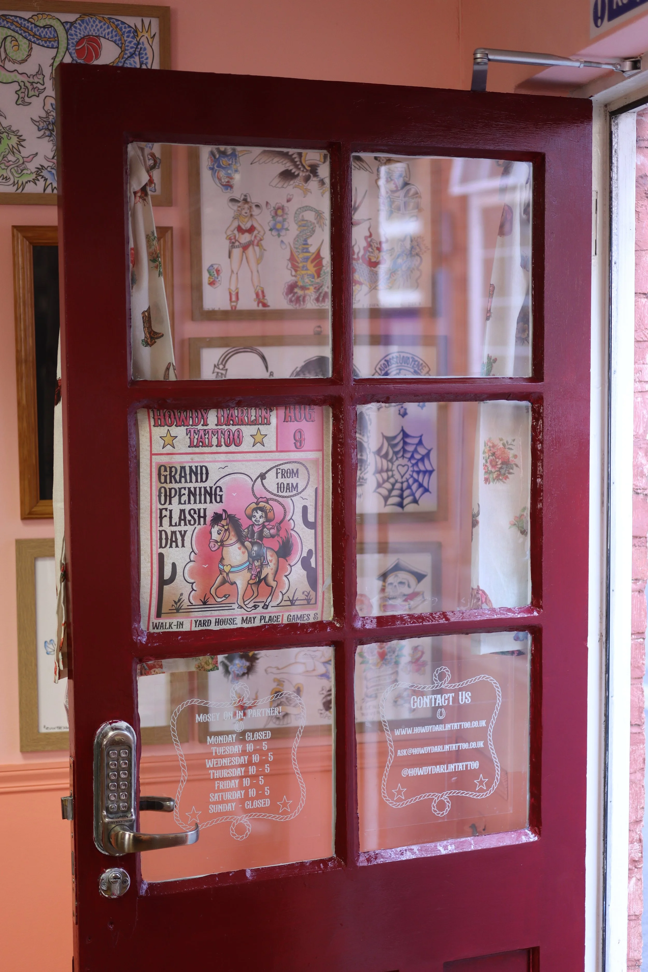 Howdy Darlin's front door. It is painted maroon, and has six glass panes. There is a flyer advertising the shop's opening day. The door opens into the building.