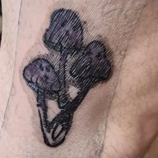 A close up image of a mushroom tattoo underneath a second skin bandage. There is a build up of plasma and black and purple ink under the bandage.