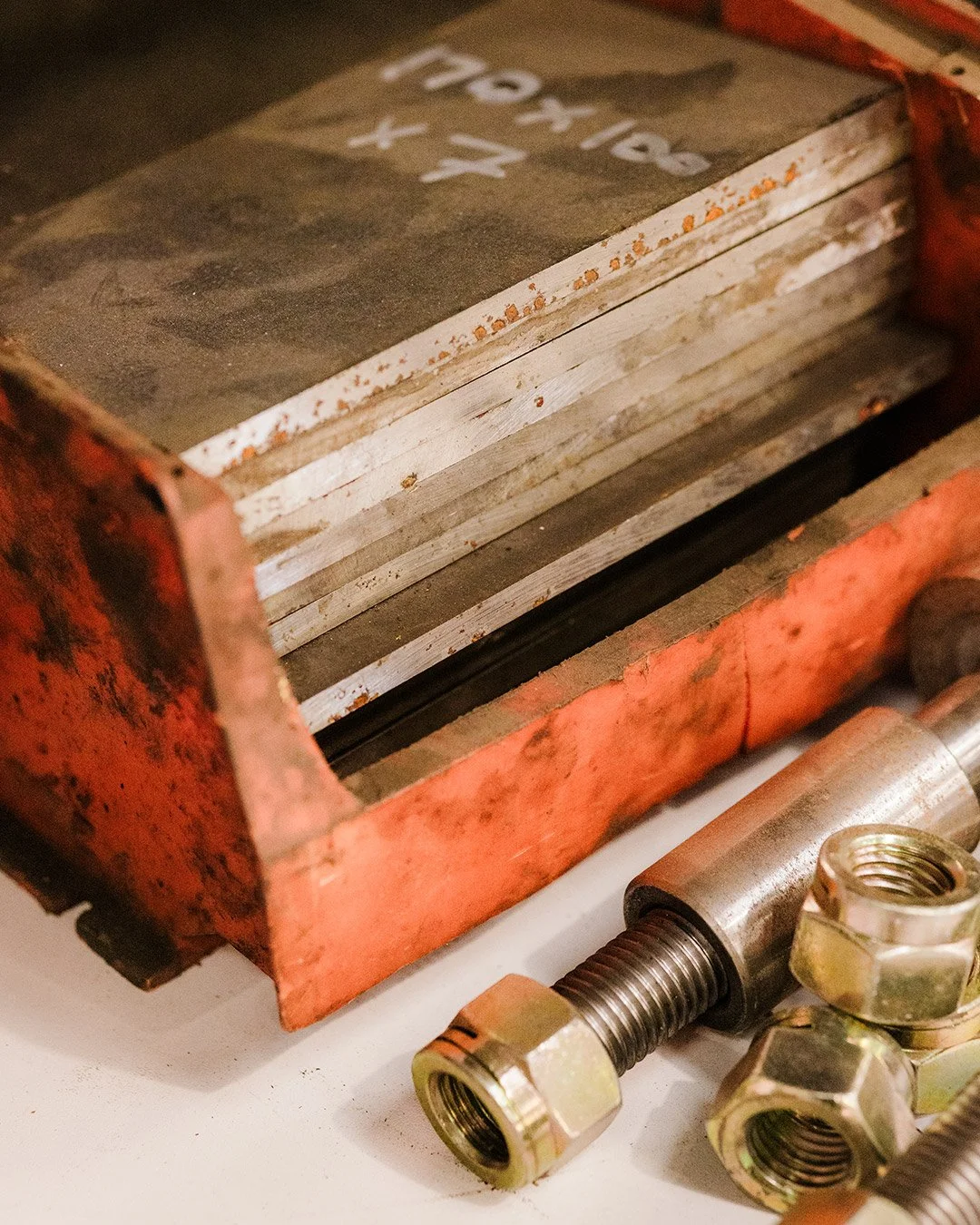 Close-up of a vintage metal hydraulic press with rust, along with metal bolts and a threaded rod.
