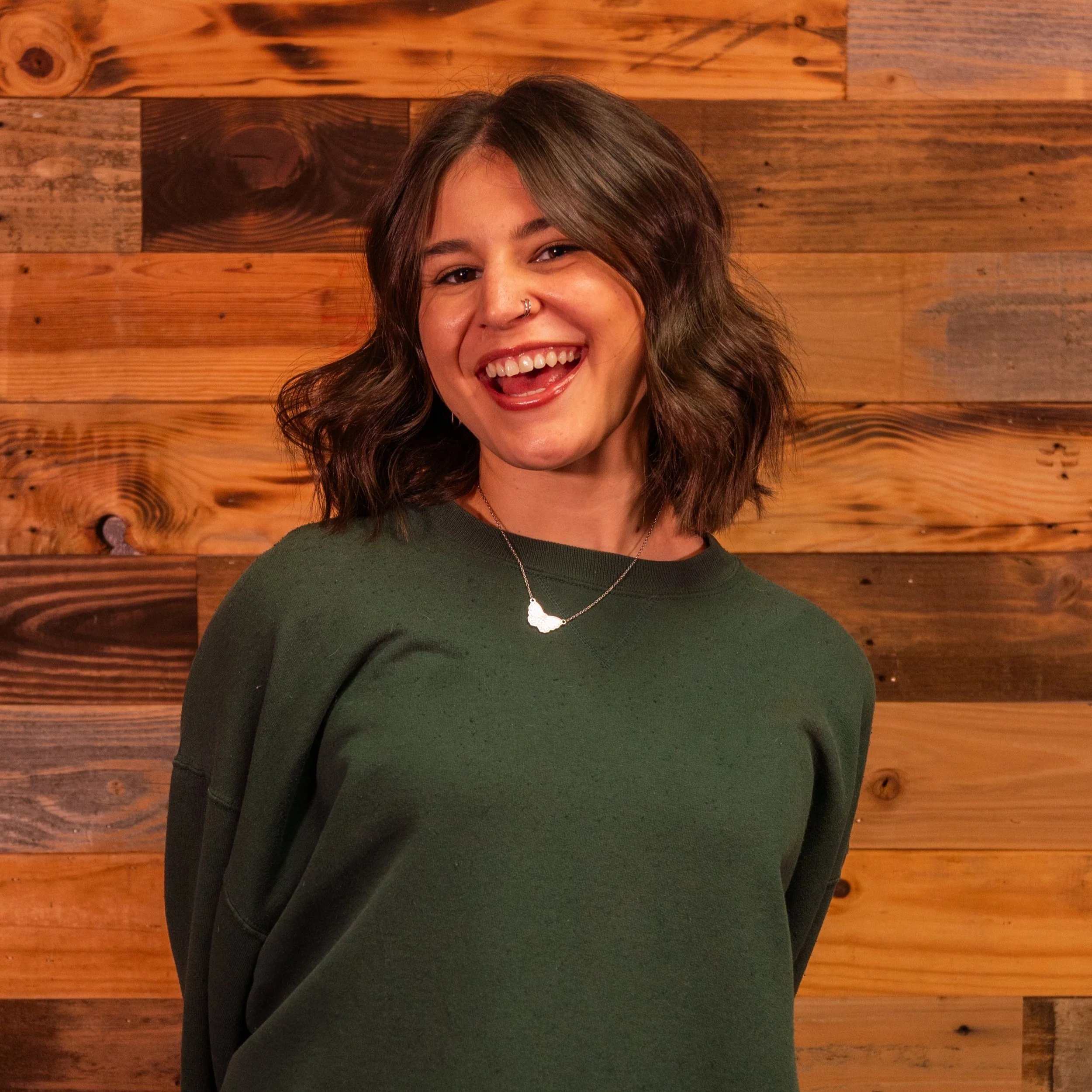 Smiling woman with long hair wearing a black top and necklace.
