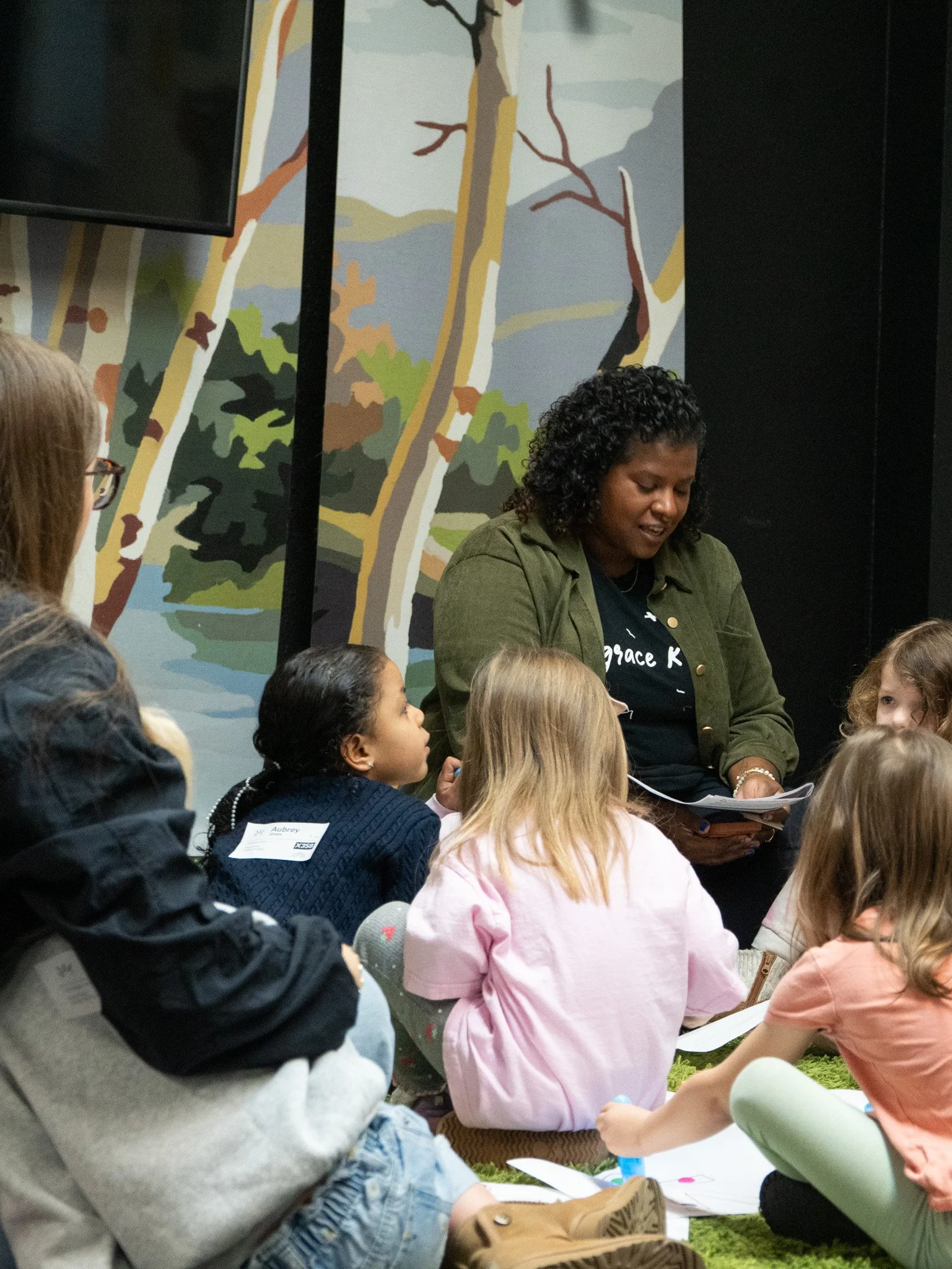 Children at a party with balloons and decorations, wearing blue T-shirts.