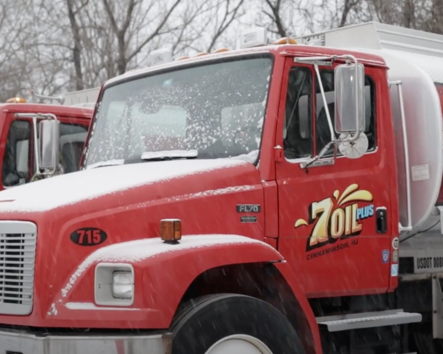 A red truck branded with 7Oil, parked outdoors in a snowy environment, with trees in the background.