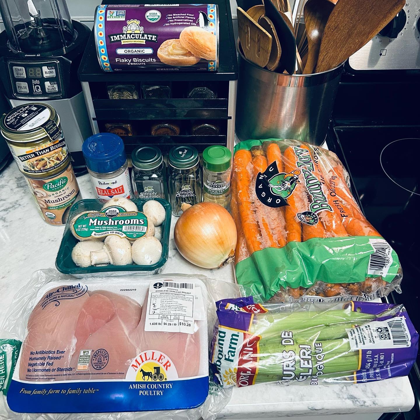 Fresh chicken breasts, carrots, onion, mushrooms, organic spices, salt, mushroom soup, and organic celery from a grocery store on a kitchen countertop.