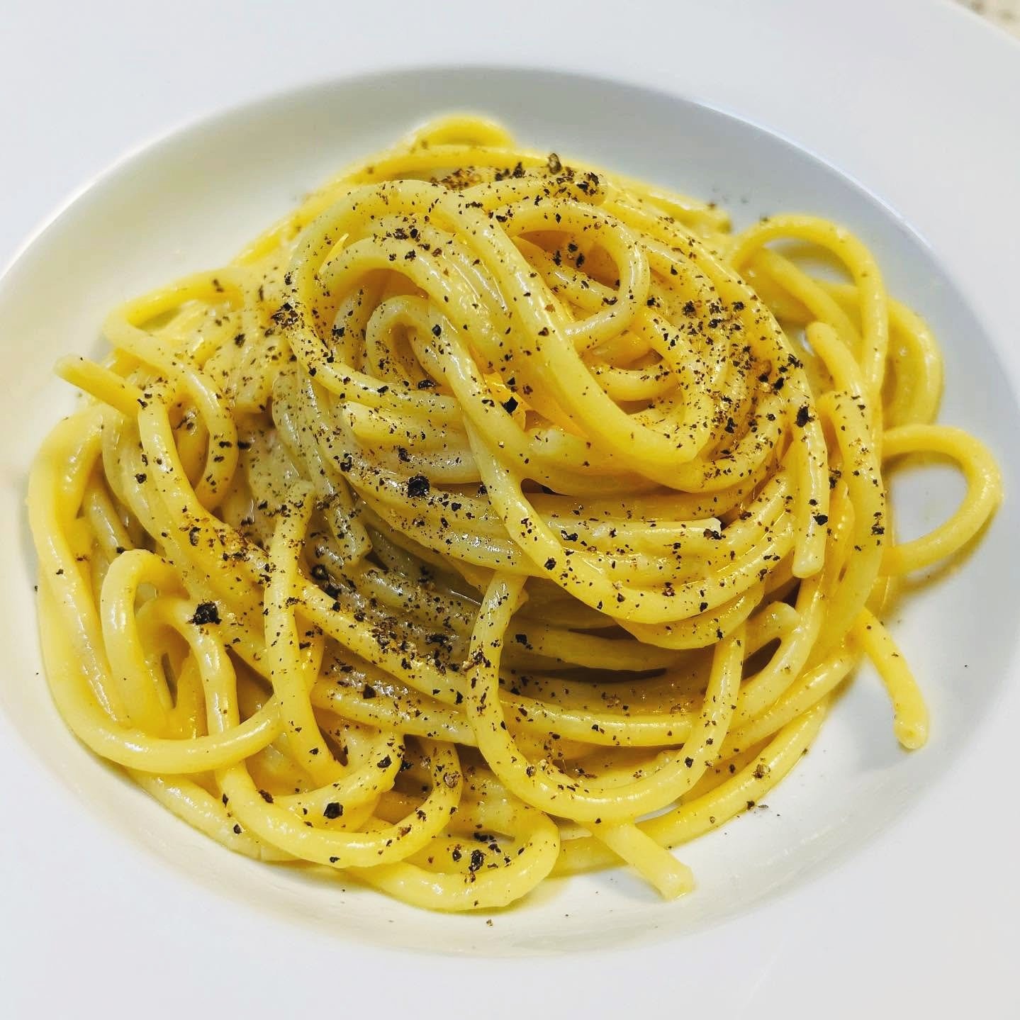 Plate of cooked spaghetti pasta topped with black pepper