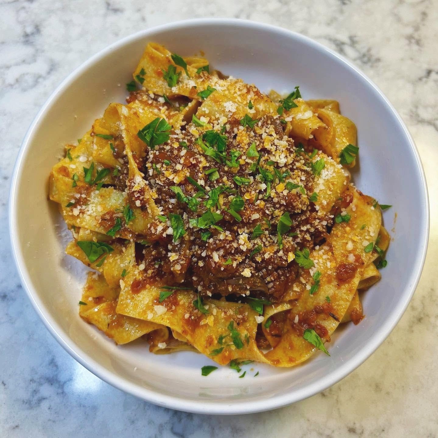 Bowl of beef and onion stuffed pasta with grated cheese and chopped parsley