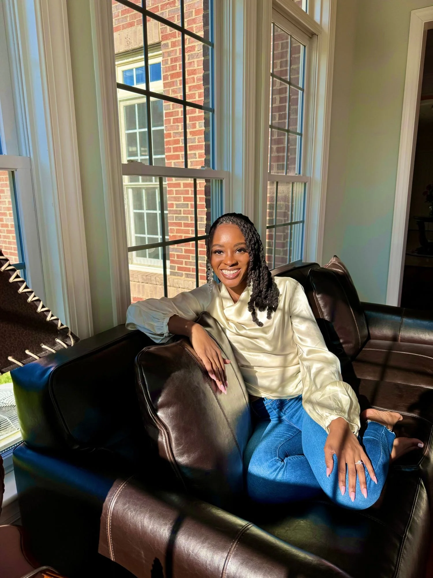 Black woman sitting on a brown couch smiling