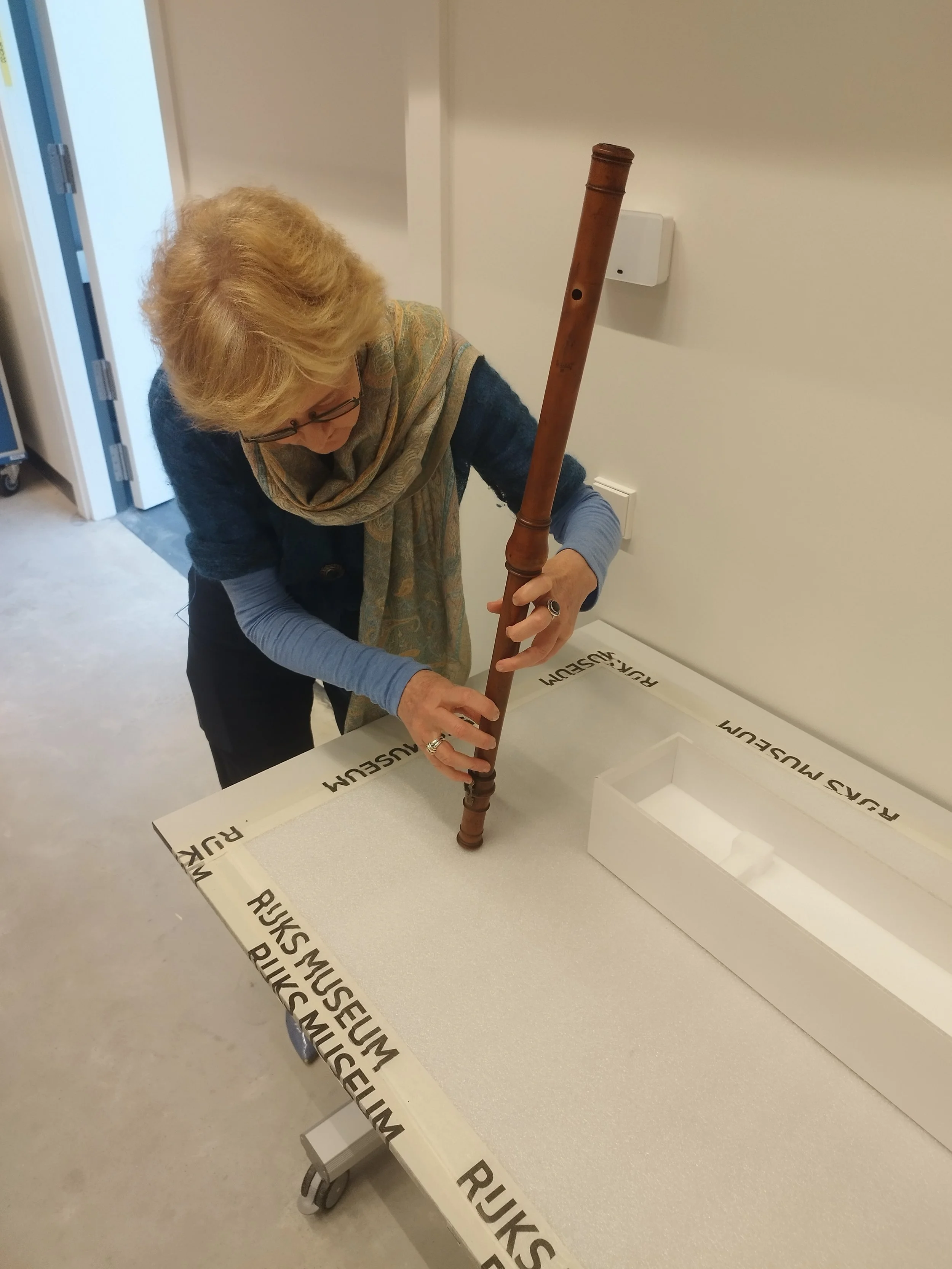 Person examining a historical flute at the Rijksmuseum.