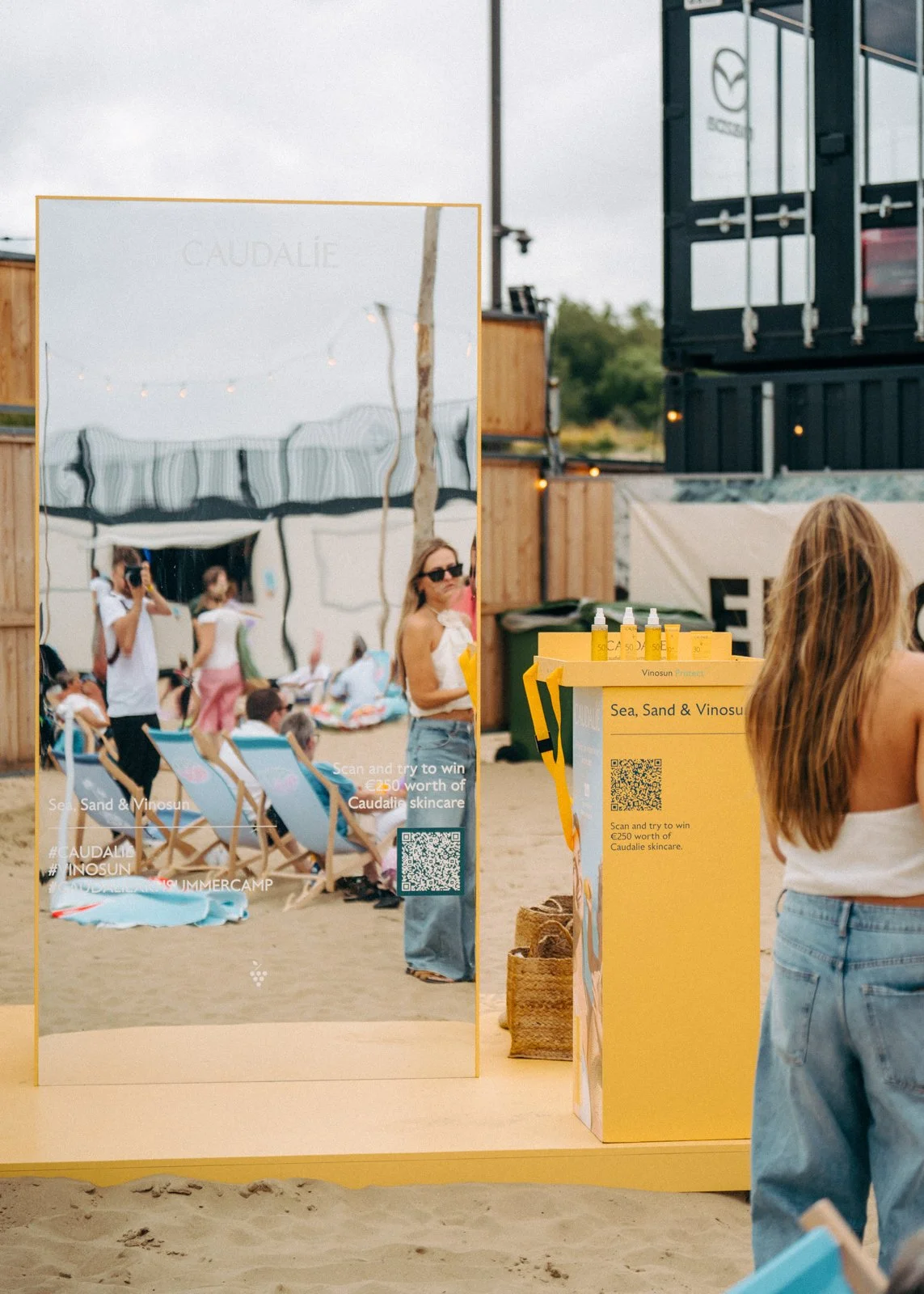 Beach activation booth with mirrored facade and interactive wheel for Caudalie brand experience in Knokke