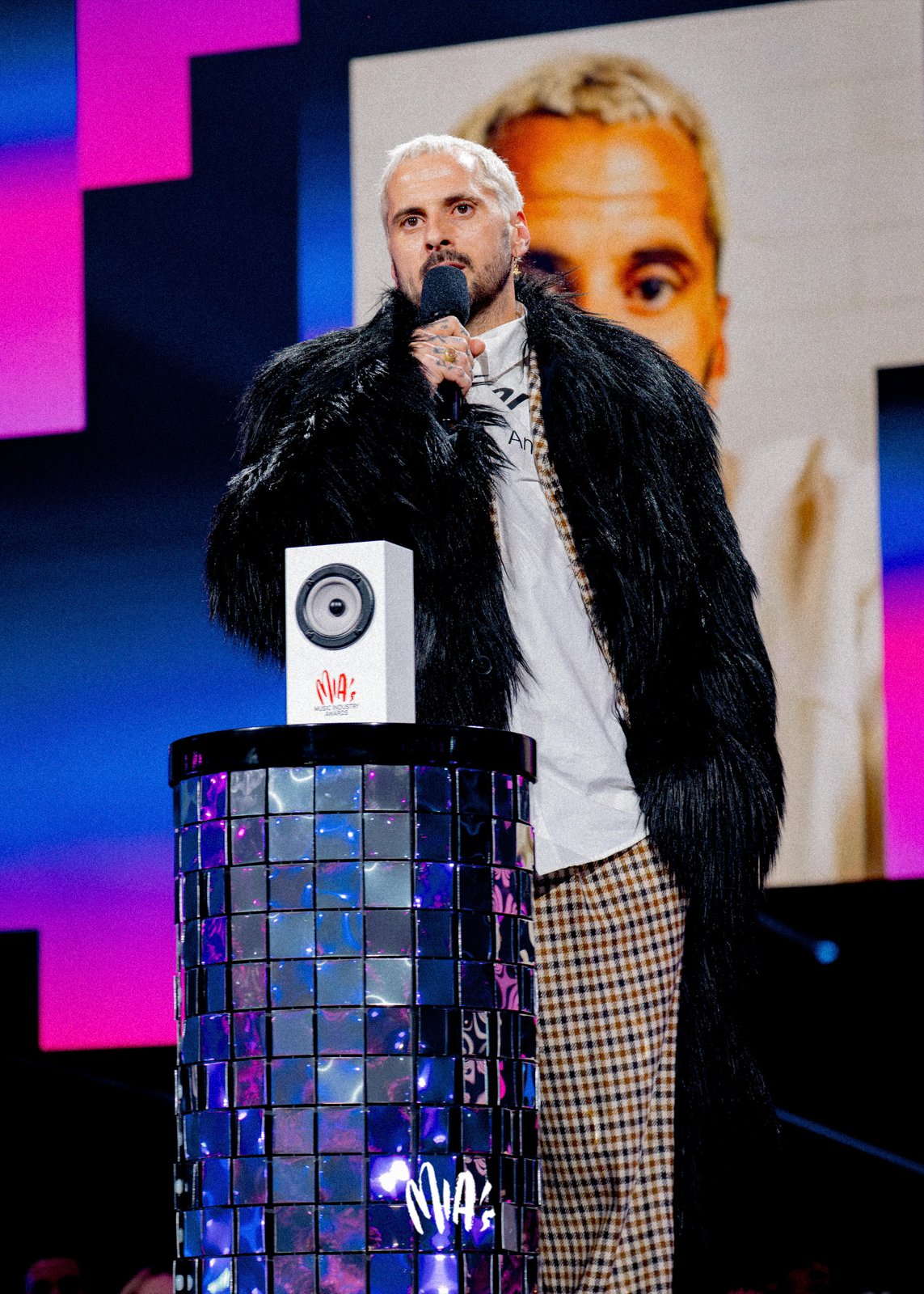 Reflective performance stage with precision lighting and camera logic for televised music awards show