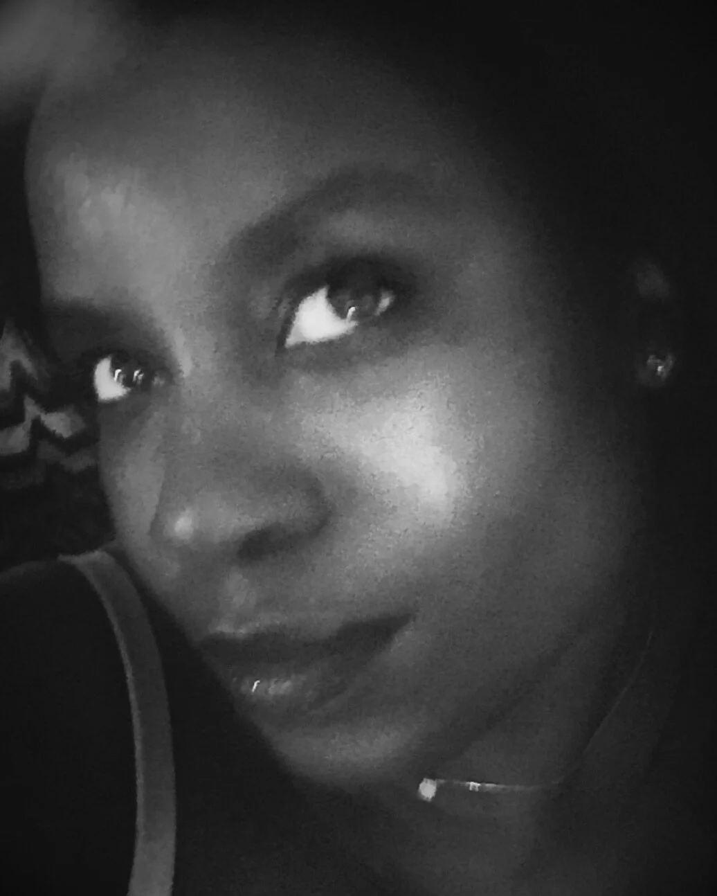 Black and white close-up portrait of a person's face, looking upwards, with focus on the eyes.