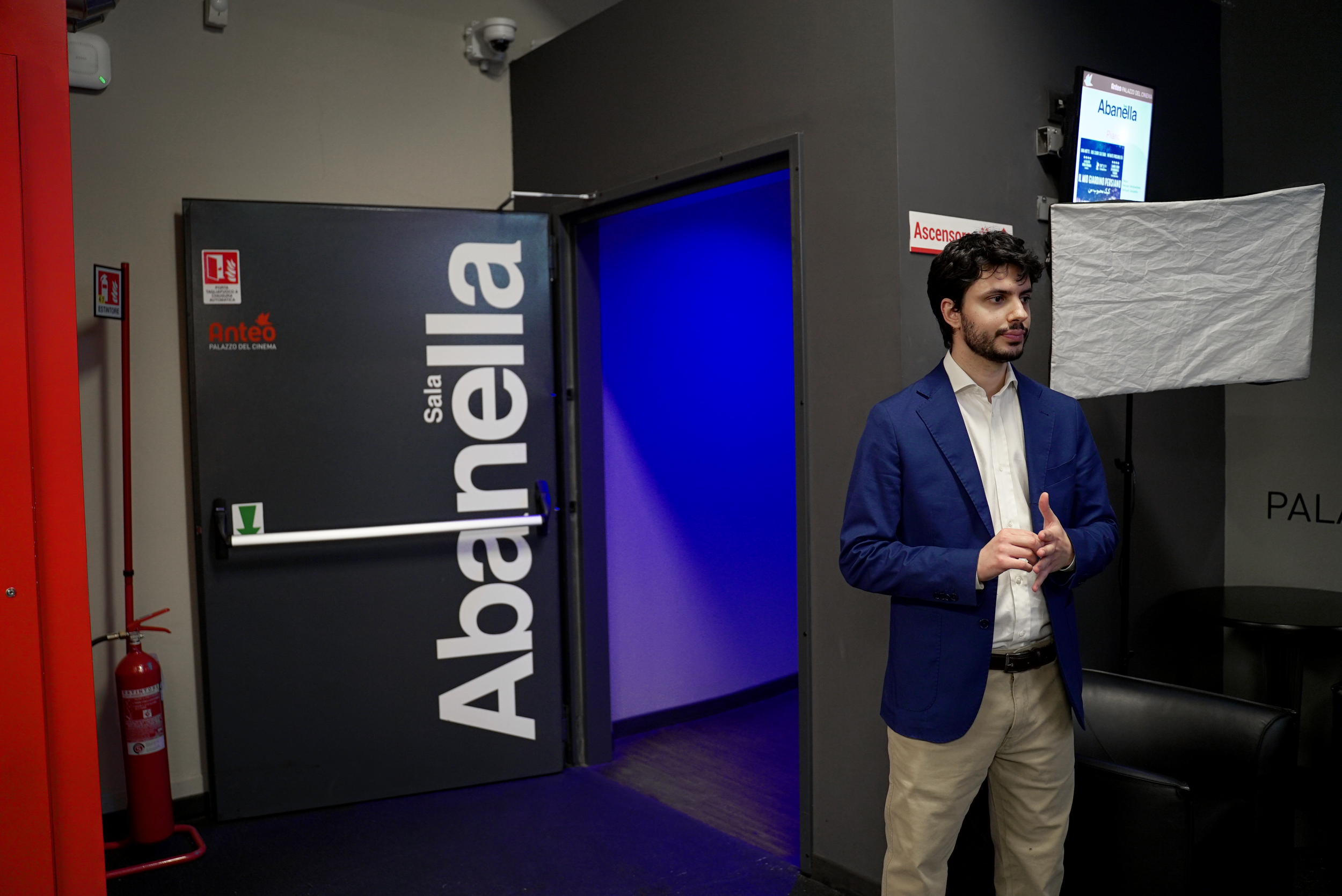 A person in a blue jacket stands in front of a door labeled 'Sala Abanella' at the Anteo Palazzo del Cinema.