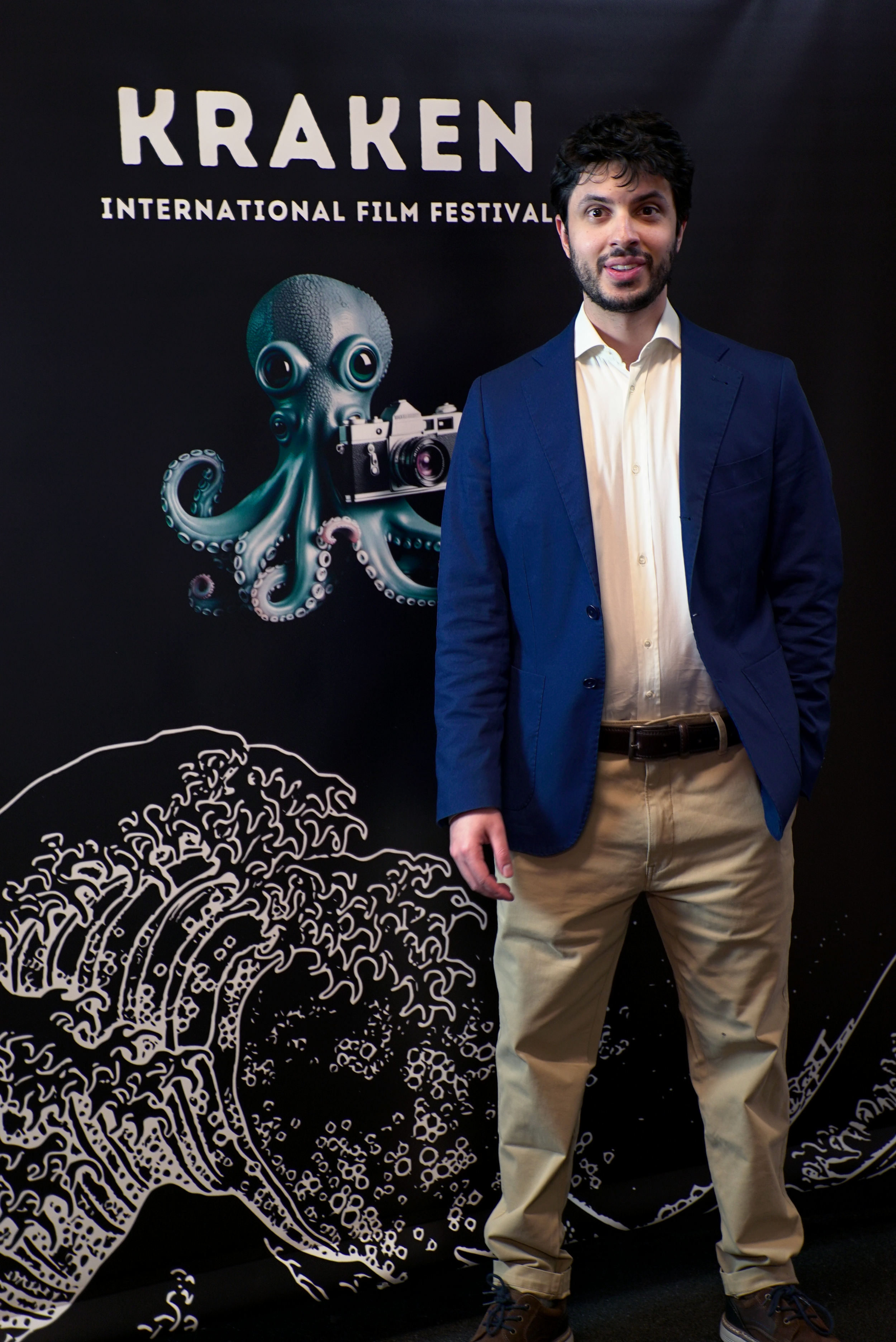 Person in front of 'Kraken International Film Festival' banner with octopus illustration holding a camera.