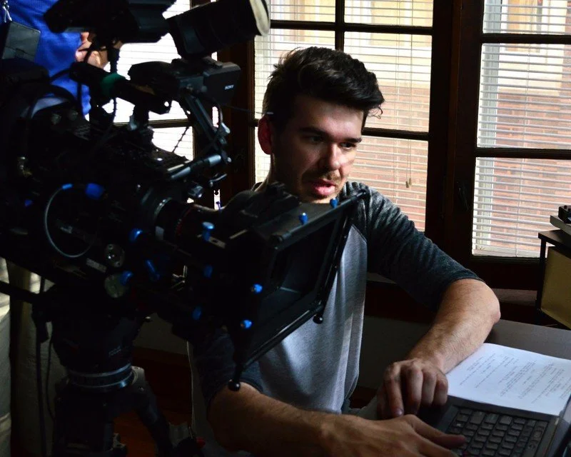 Person operating a film camera indoors next to a window