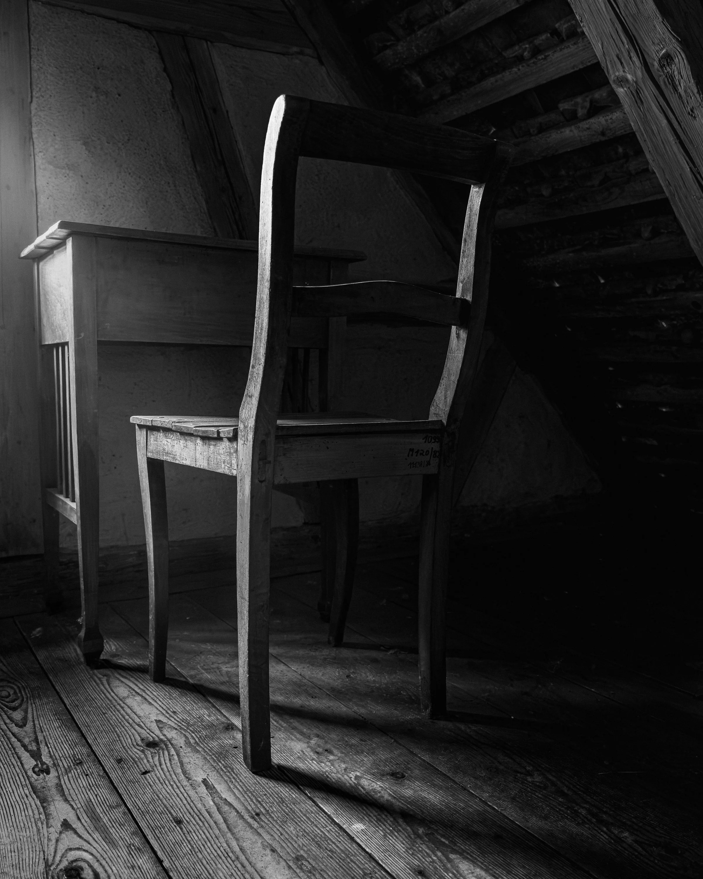 Schwarzer und weißer Holzstuhl in einem dunklen Raum mit Holzboden