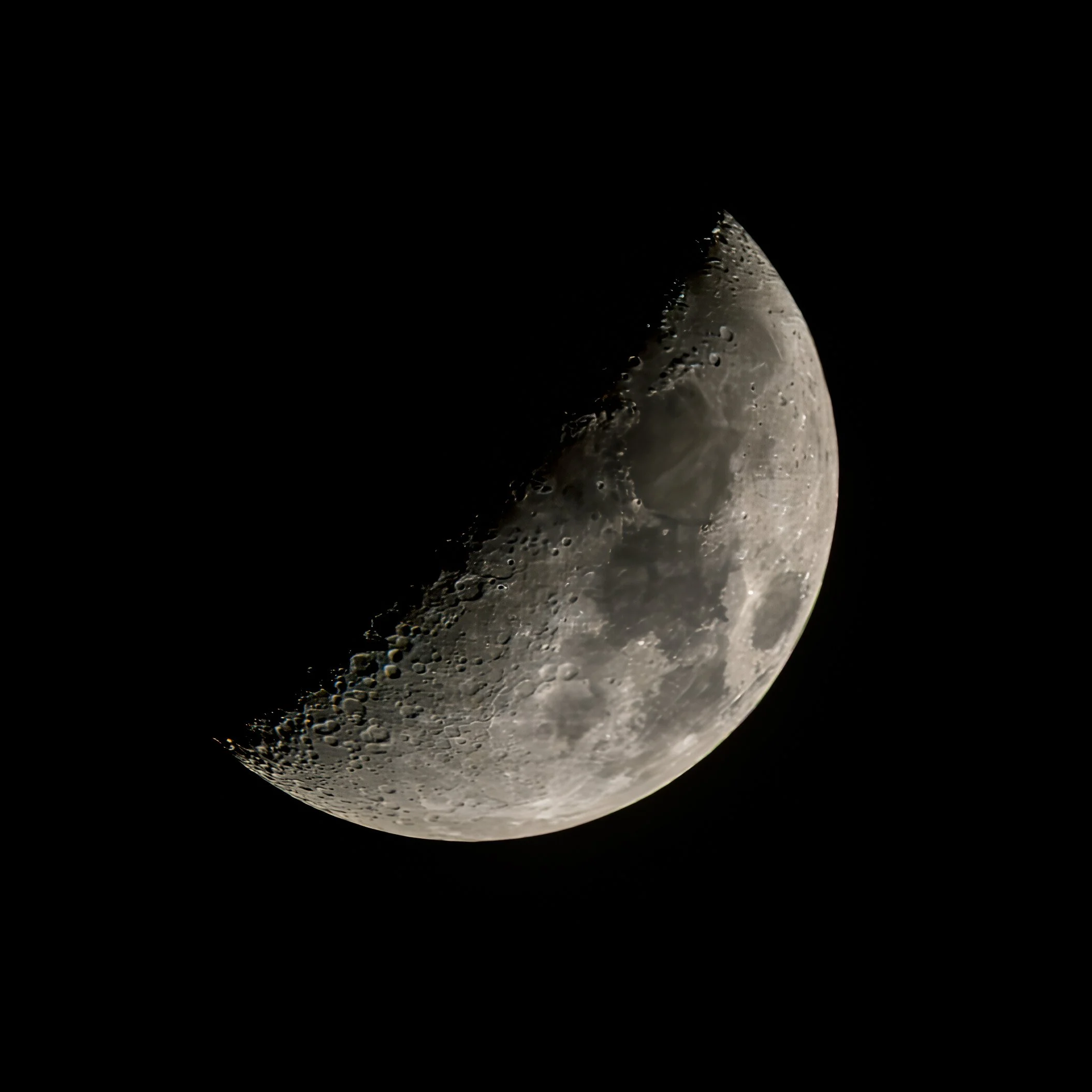 Nahaufnahme des Mondes mit sichtbaren Kratern und Details auf seiner Oberfläche, teilweise vom Schatten bedeckt.