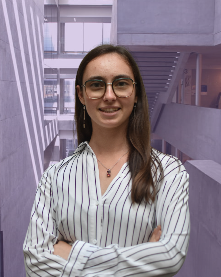 Man in a dark suit smiling outside a modern building