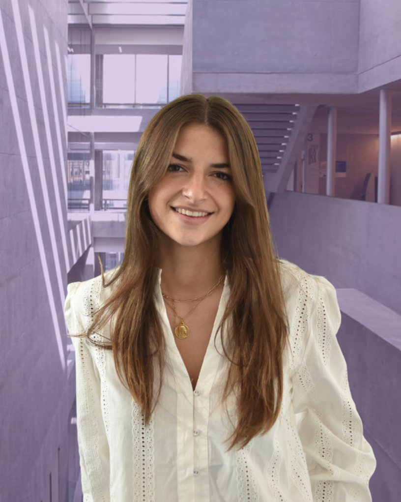 Person with long hair in a black blazer standing outdoors with a modern building in the background.