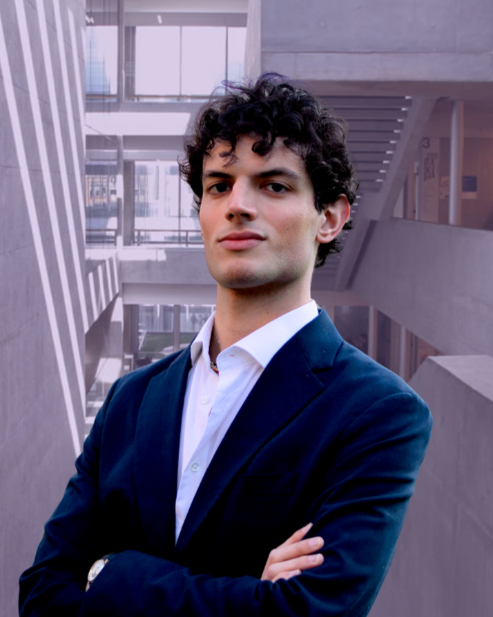 Man in a blue suit with arms crossed standing outside a modern building with vertical lines.