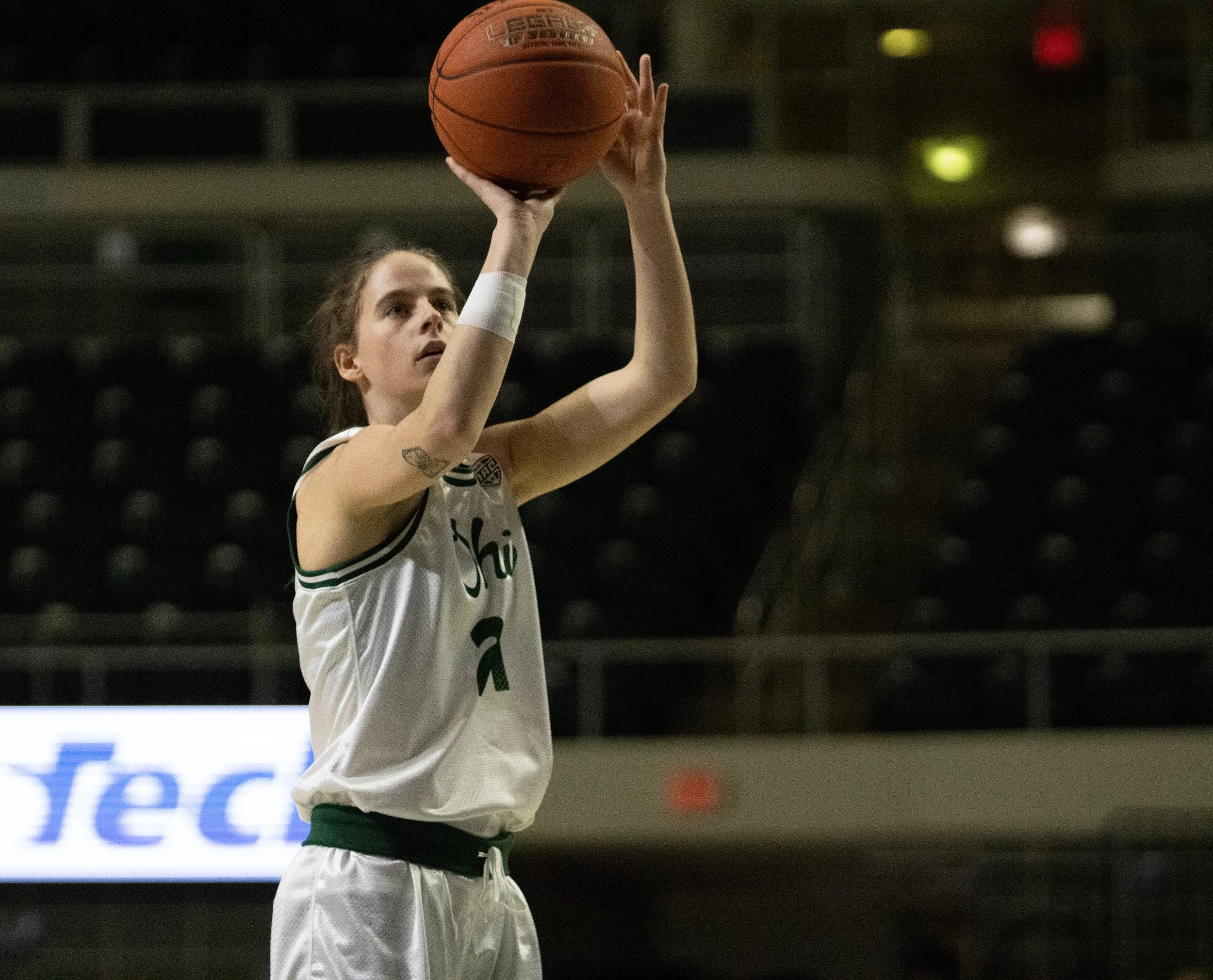 A female basketball player preparing to take a shot in an indoor basketball court.