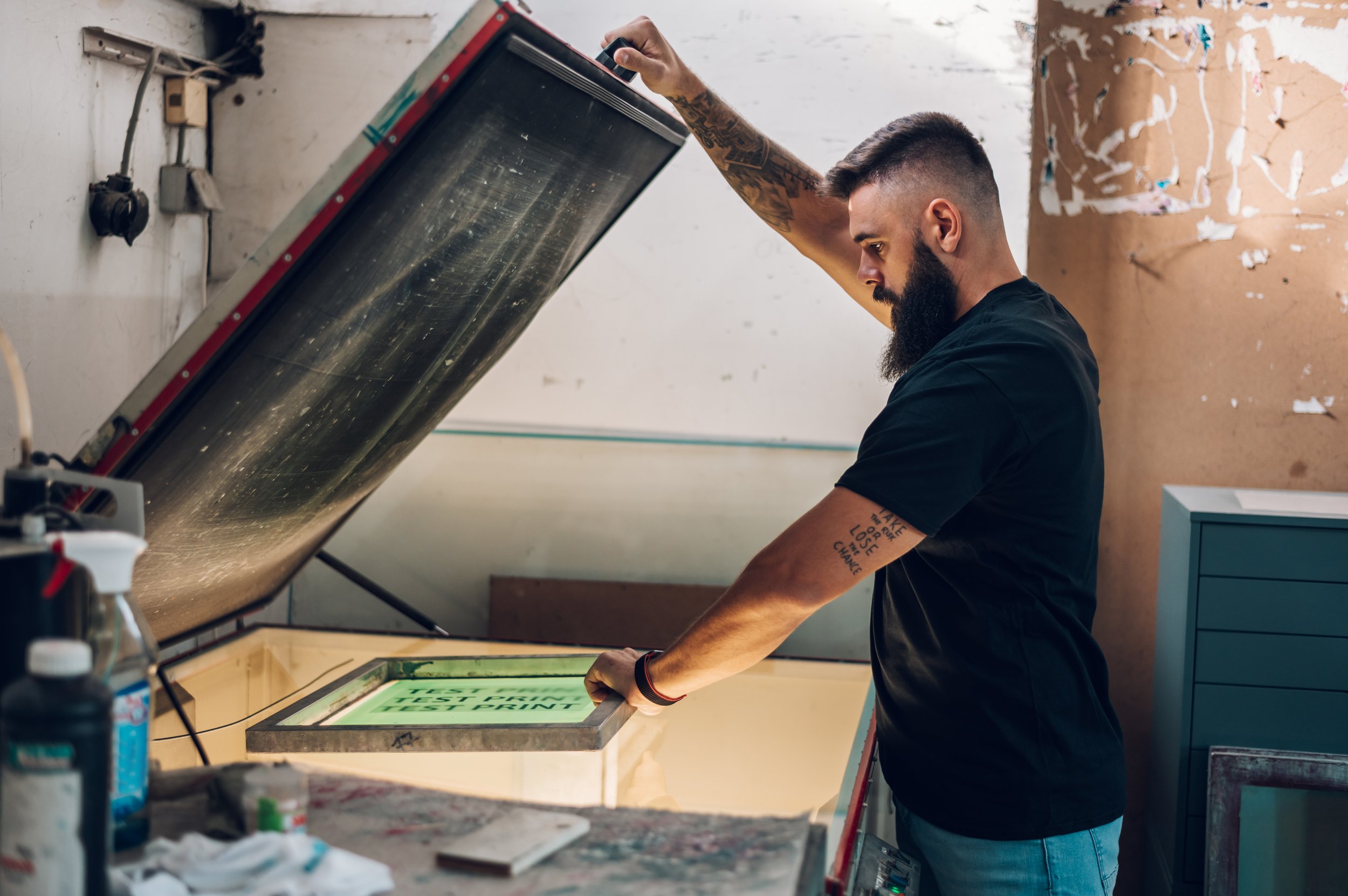 Man using a screen printing machine in a workshop