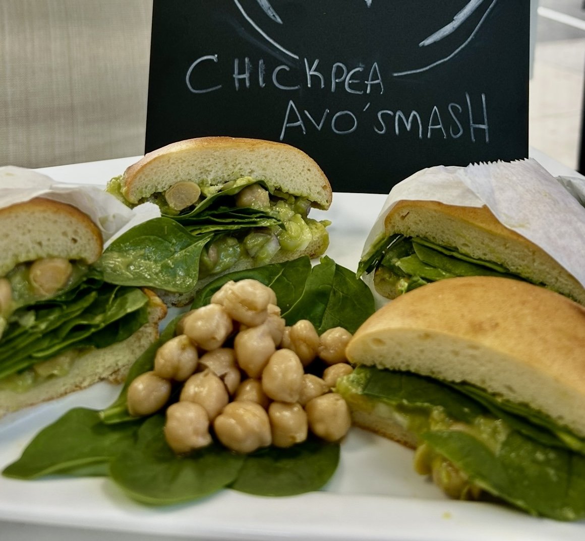 Chickpea avocado smash sandwiches with spinach and chickpea garnish on a plate.