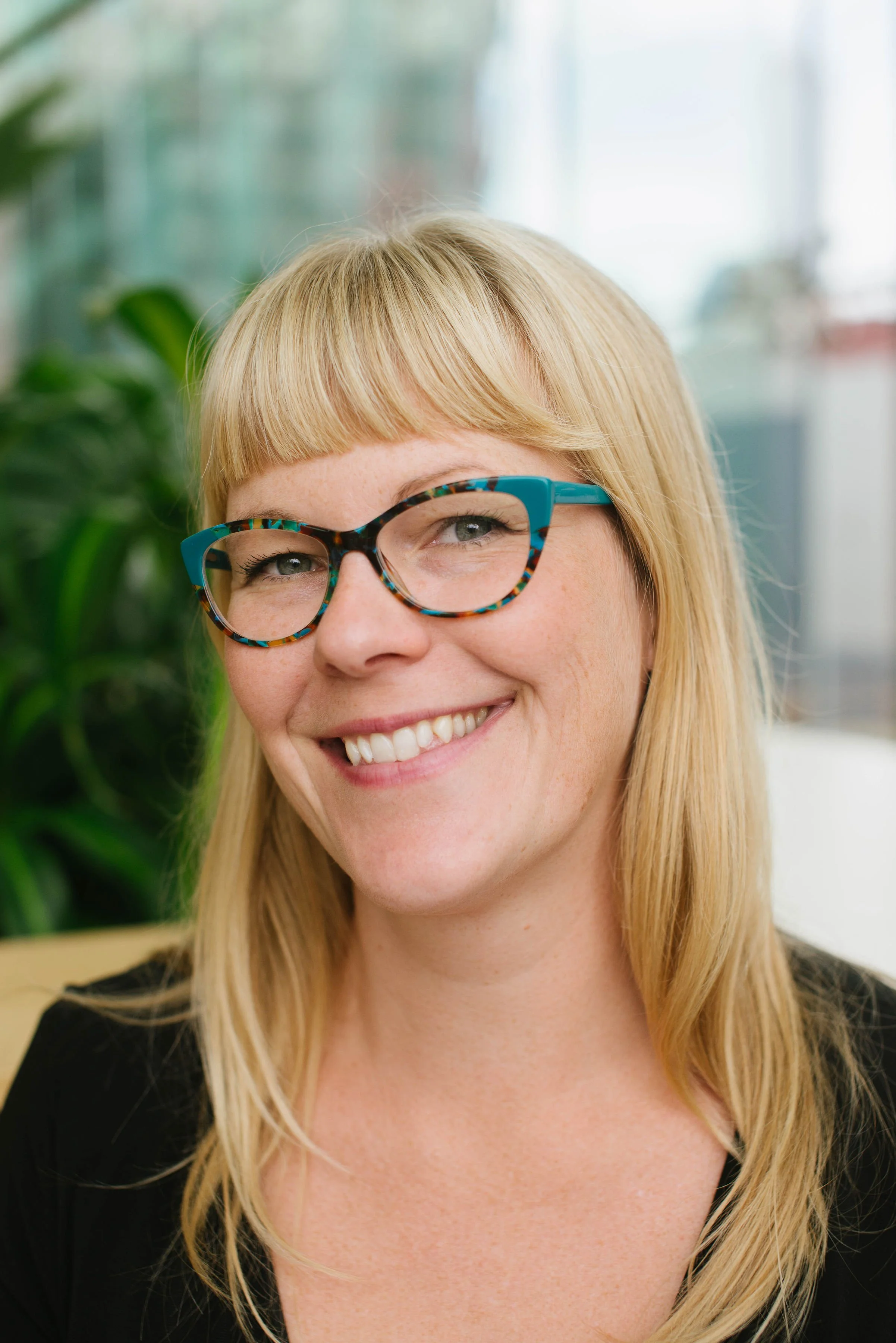 A woman with blonde hair and glasses smiling.
