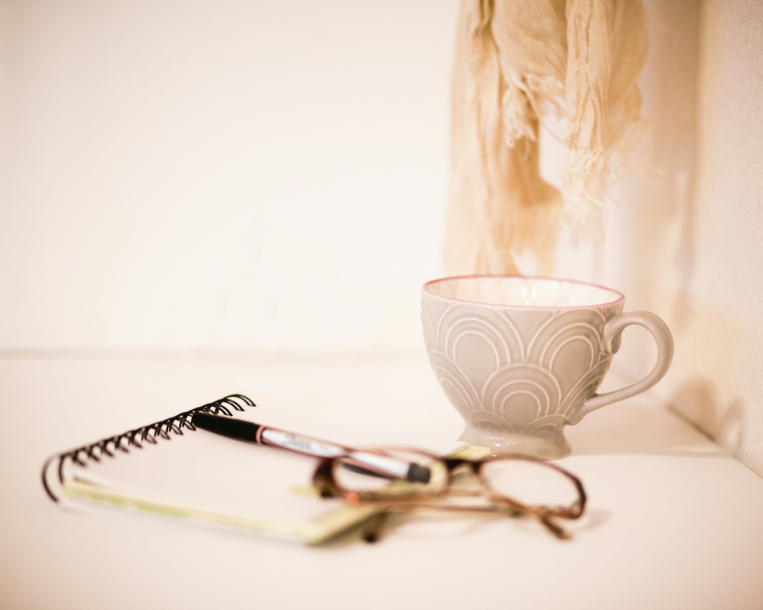 Image of a cup of tea next to a notebook, pen and glasses. If you or someone you know is navigating the loss of a loved one, these organizations provide counselling, education, and community support.