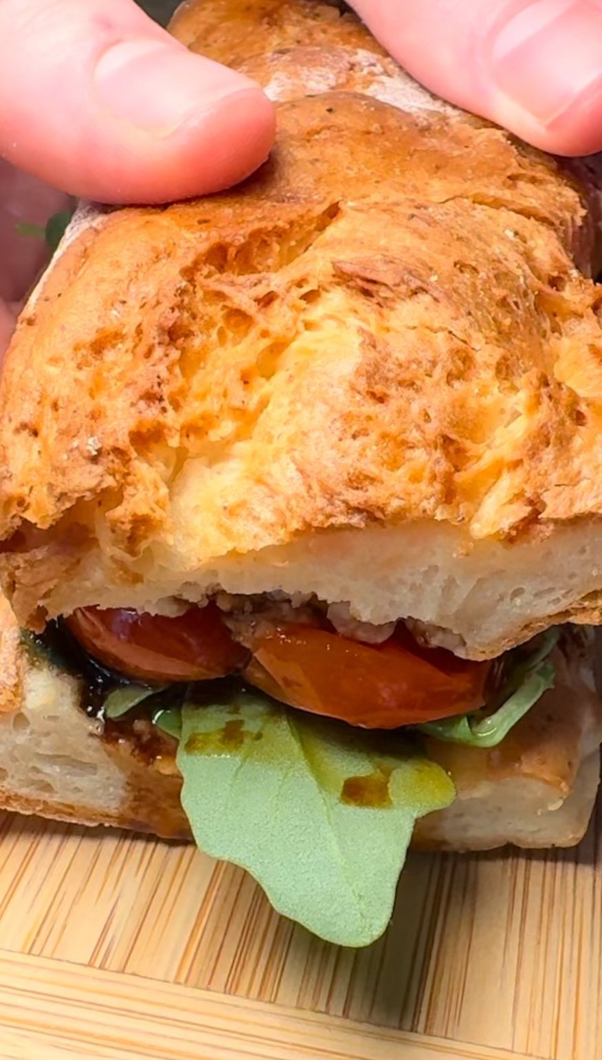 Close-up of a sandwich made with toasted bread, visible lettuce, tomato slices, and other ingredients inside.