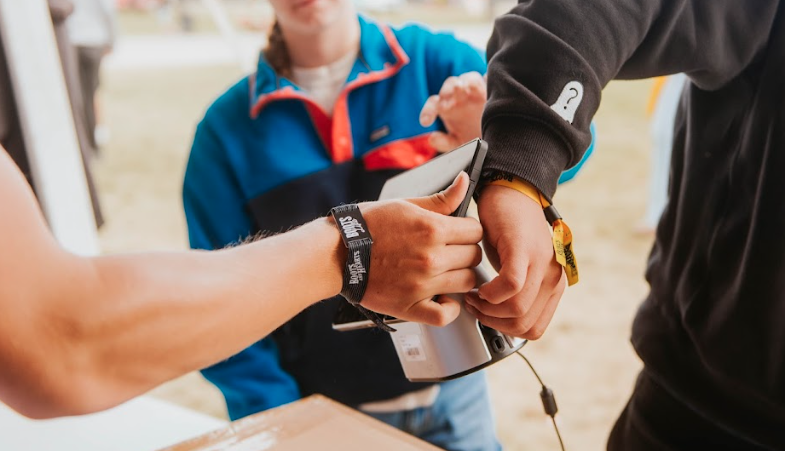 Close-up of a person holding a device, possibly a card reader, with another person scanning a card or ID badge.