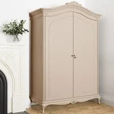 A beige armoire with decorative molding stands against a white wall in a room with hardwood floors.