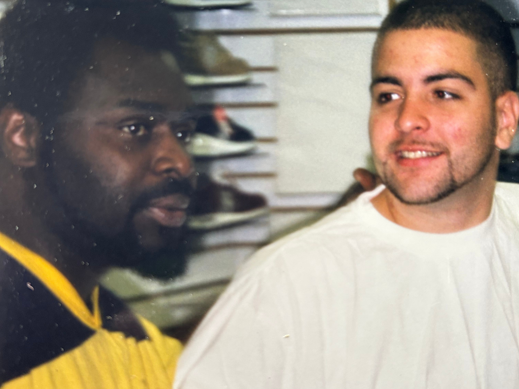 Two men in a shoe store, one wearing a yellow and black sports jersey and the other wearing a white T-shirt, engaging in a conversation.