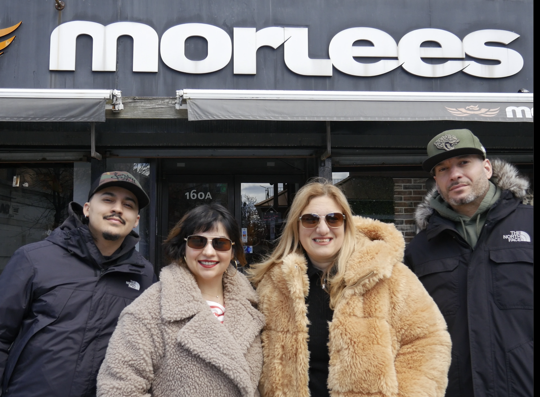 MORLEES Staff 2025 . Four people standing in front of a store with the sign 'morlees,' wearing winter jackets and sunglasses.