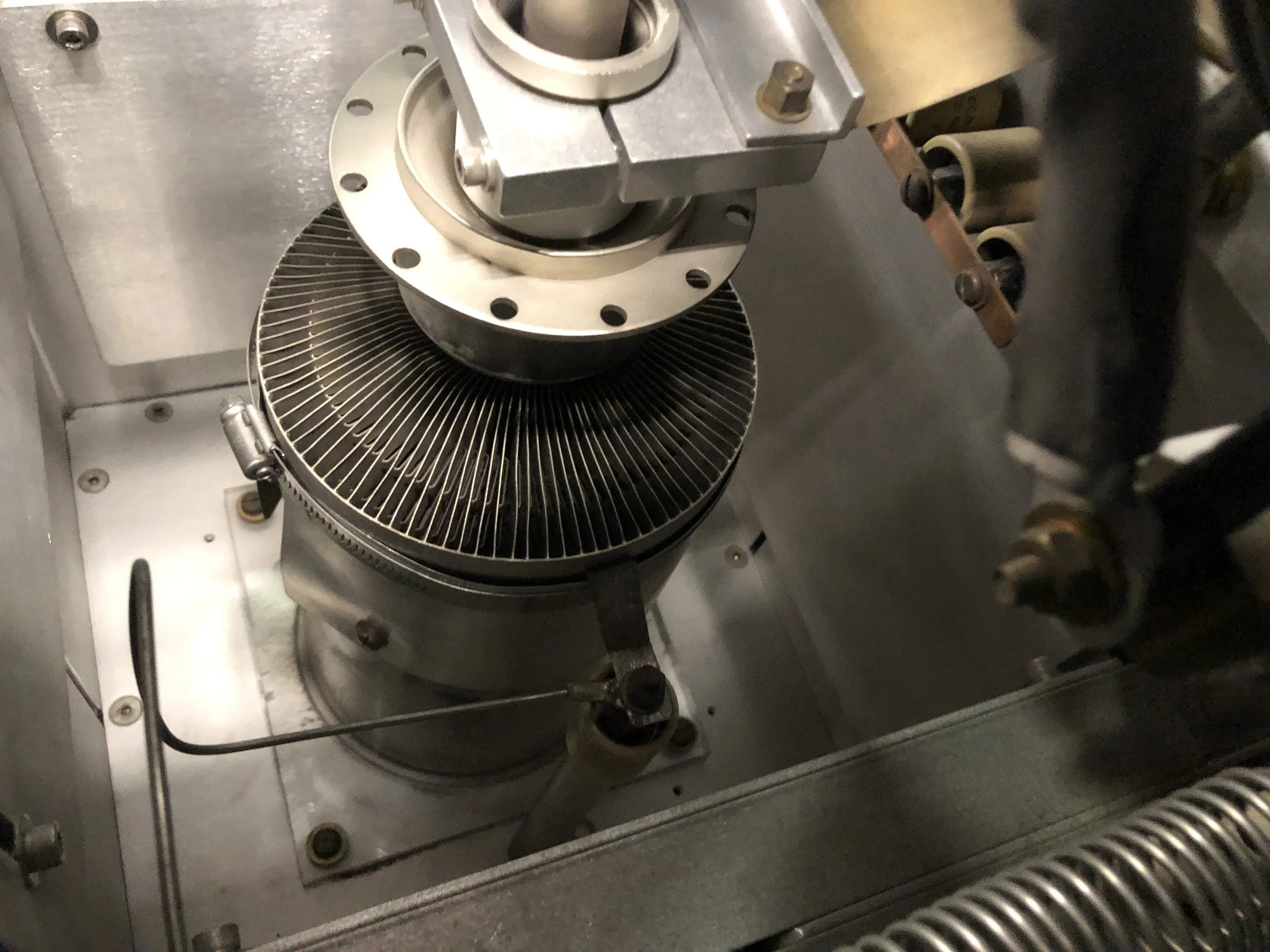 Close-up of industrial machinery with metal components and a fan-like structure inside a metal casing.