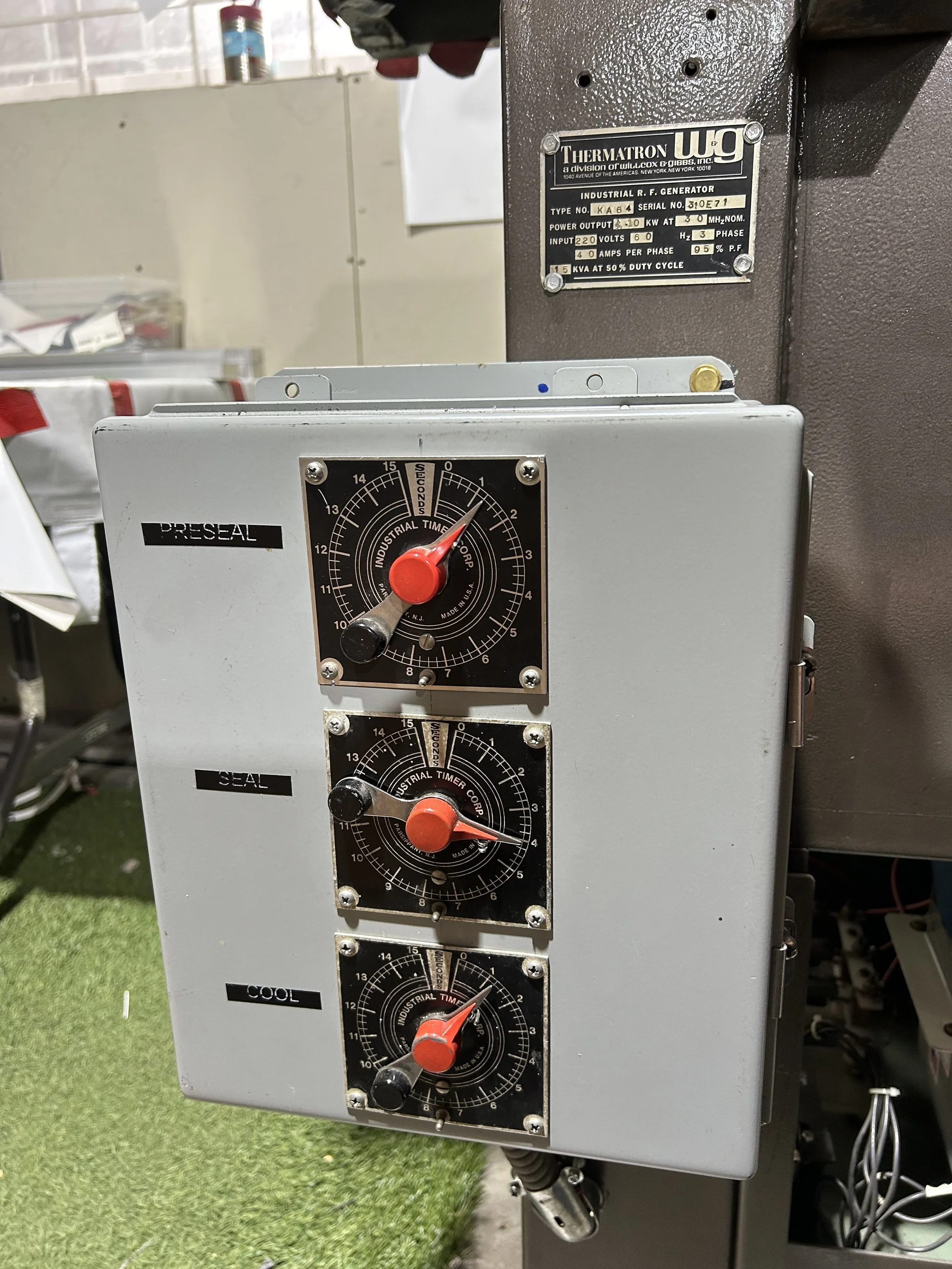 Control panel with three industrial dials labeled Preseal, Seal, and Cool; mounted on a machine with a metal plaque showing "Thermatron WIG."