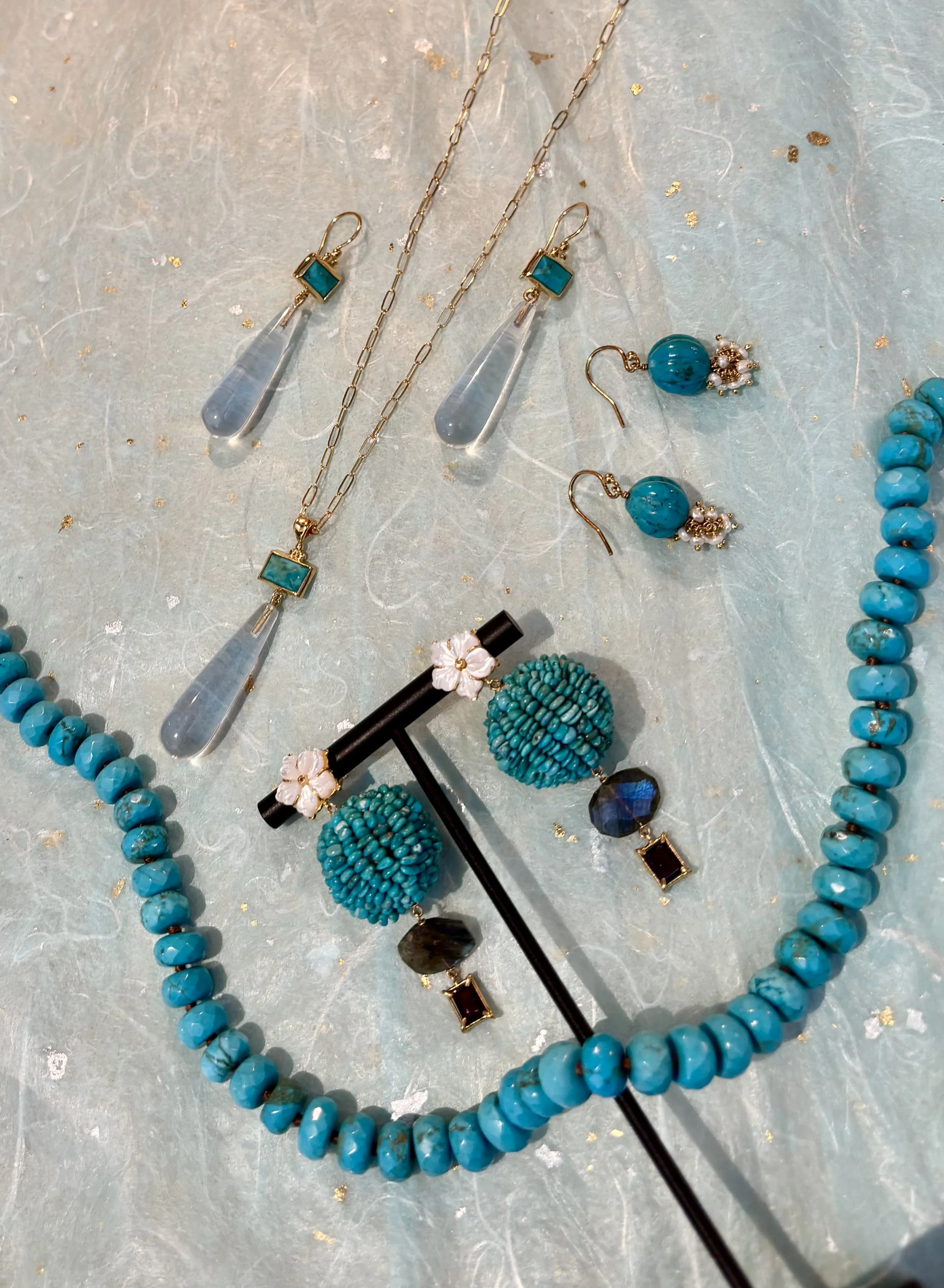 Clothing store interior with racks of colorful garments, a wooden mirror, a table displaying folded clothes, accessories, and magazines. Cozy sofa with cushions and soft lighting.