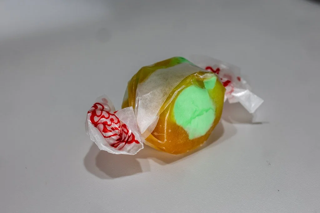 Caramel Apple flavored taffy with clear wrapper and red lettering on the ends. an almost opaque tan outside with green center piece of taffy.