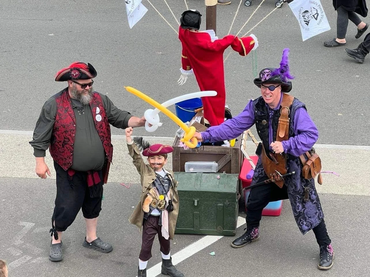 2 men dressed as pirates with balloon swords with a small boy dressed as a pirate enjoying pirate daze festival in westport, washington