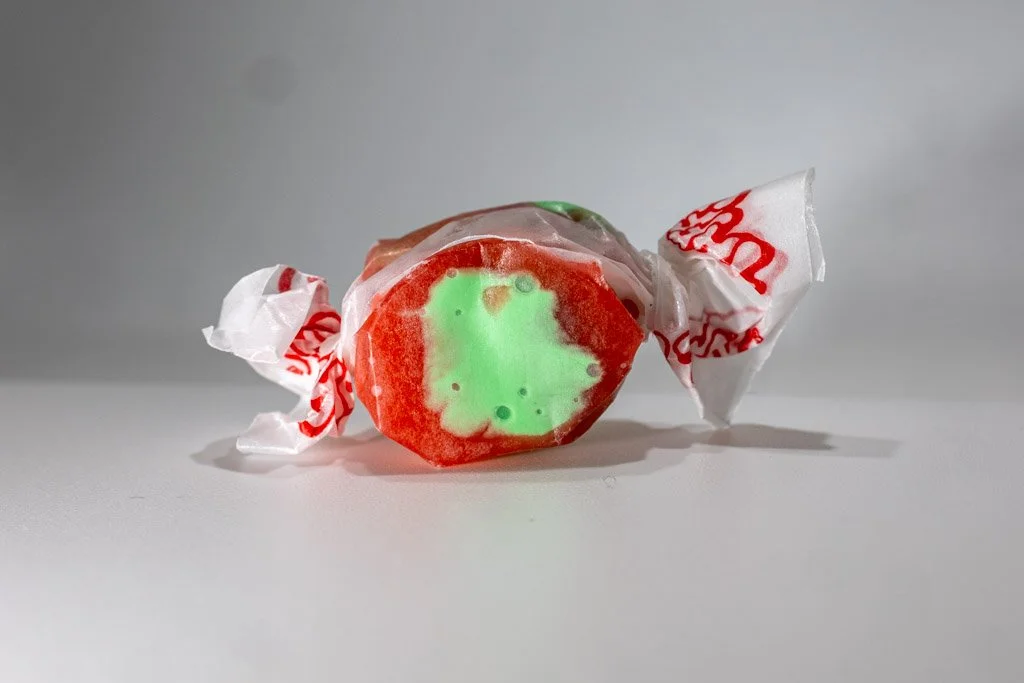 Candy Apple flavored taffy in clear wrapper with red lettering on the ends. bright red taffy with a green center