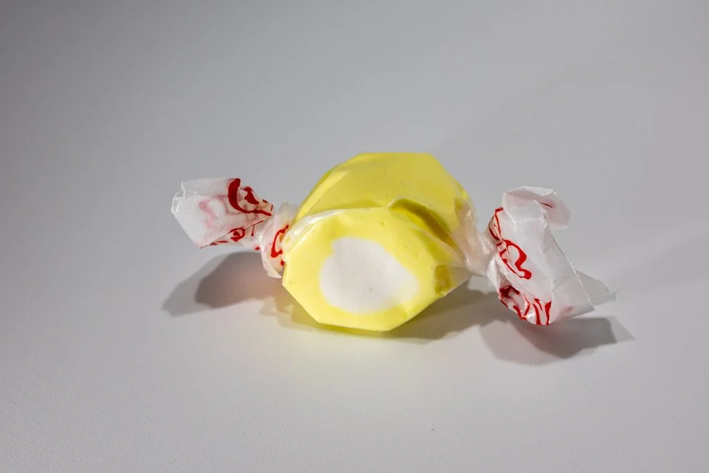 Yellow and white lemon cream saltwater taffy from Sea Bird Gifts & Candy in Westport WA. Bright citrus taffy with a creamy center, wrapped in wax paper.