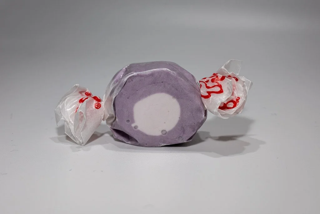 Purple and white huckleberry saltwater taffy from Sea Bird Gifts & Candy in Westport WA. Smooth, fruity taffy wrapped in wax paper with bold berry flavor.