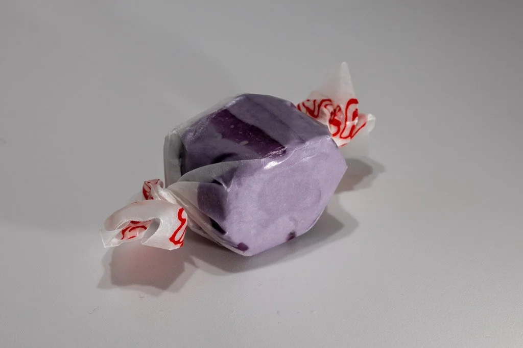 Purple grape saltwater taffy from Sea Bird Gifts & Candy in Westport WA. Vibrant taffy wrapped in white wax paper with red print.