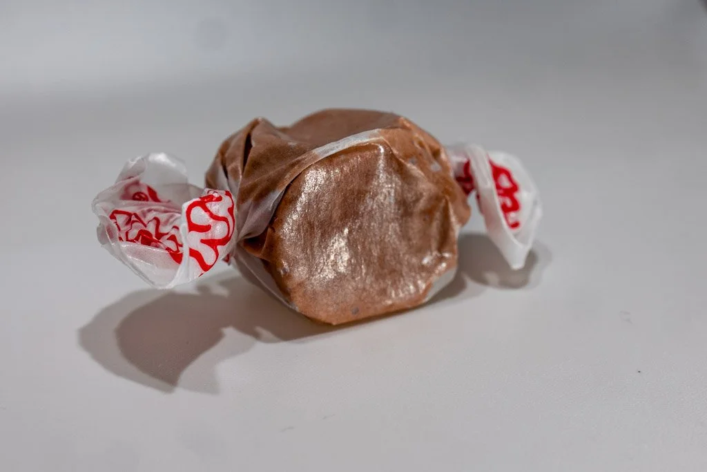 chocolate flavored taffy in clear wrapper with red lettering on the ends. a deep brown colored piece of taffy