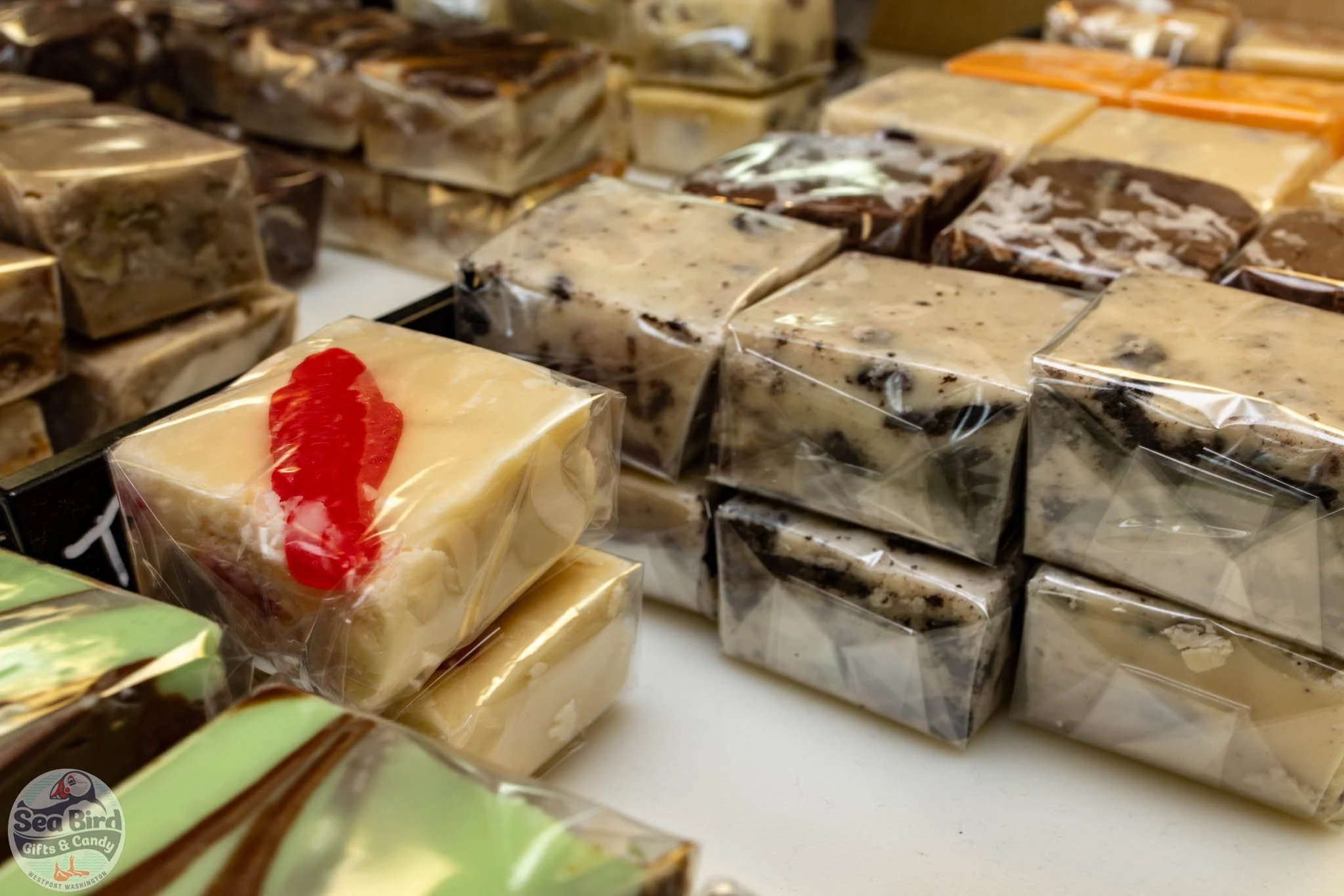 Assorted handmade soaps wrapped in plastic, displayed on a table at a store called Sea Bird Gifts & Candy in Washington.