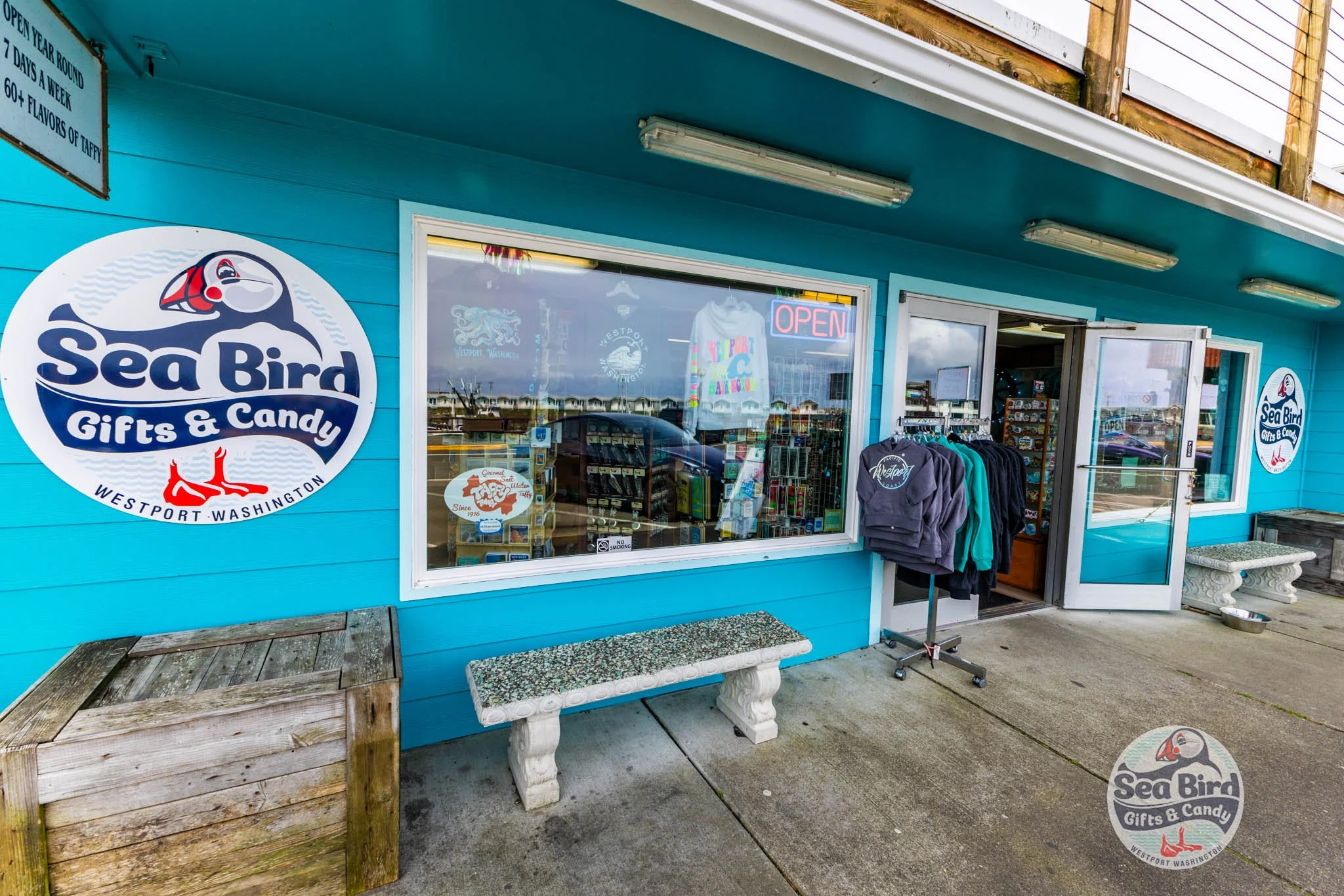 Sea Bird Gifts & Candy storefront in Westport, Washington, with bright blue exterior, open door, window displays, clothing rack, and Sea Bird logo sign outside the shop.